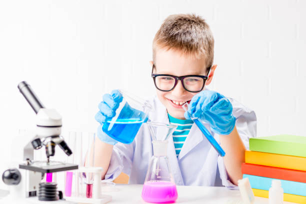 istock A schoolboy with a microscope and book examines chemicals in test tubes, conducts experiments - a portrait on a white background. Concept for the study of coronavirus in the laboratory 1355188820