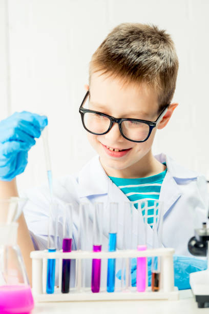 istock A schoolboy studies multi-colored substances in test tubes, conducts experiments - a portrait on a white background. Concept for the study of coronavirus in the laboratory 1355188828