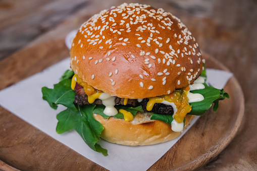 Close up shot of a slow cooked beef brisket burger with mustard,mayonnaise and some rucola.