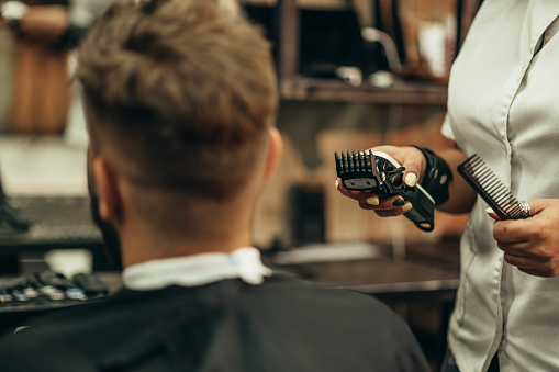 Professional barber holding a hair trimmer in her hands