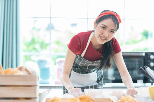 istock portrait woman with apron rolling out dough or flour on kitchen table 1355193439