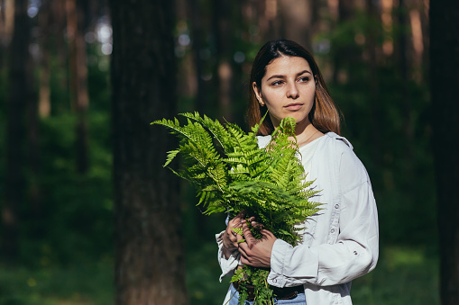 A woman in the woods hugs a bouquet of ferns, a young activist protects the forest