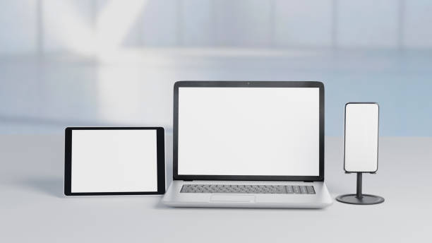 istock 3D Illustration blank screen silver laptop with smartphone and tablet computer on white desk and blur background. Selective focus image. Mockup responsive display. 1355197294