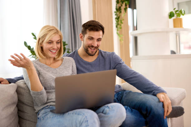 istock Young couple using a laptop while relaxing on the sofa at home 1355200285