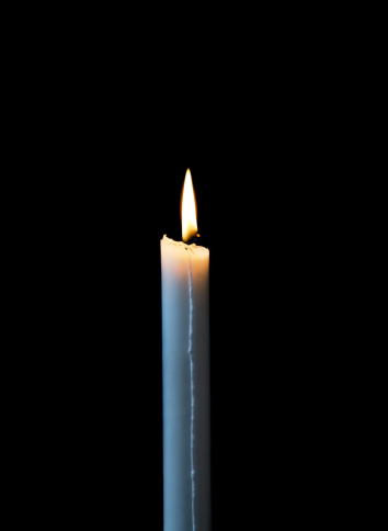 A single lit candle.Symbol for hope, peace or religion. Dark background. Photos taken in a church