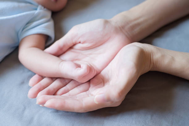 istock Baby hand with mother hands on bed 1355201540