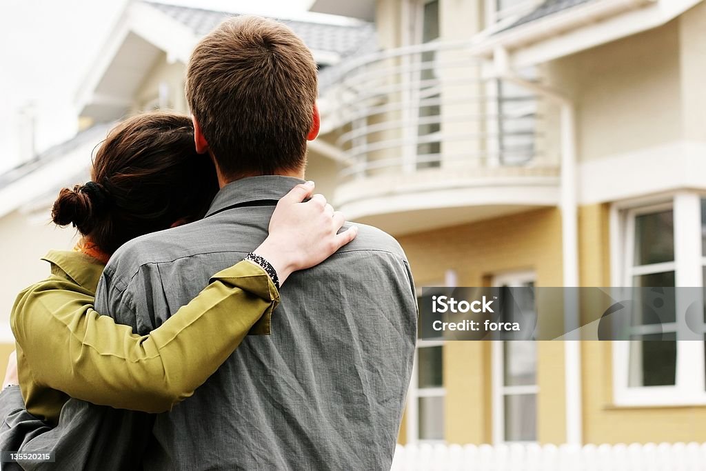 Man and woman hugging in front of a house couple in front of one-family house in modern residential area House Stock Photo