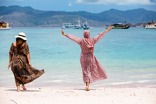 two young asian woman enjoy vacation at pink beach in padar island, nusa tenggara timur
