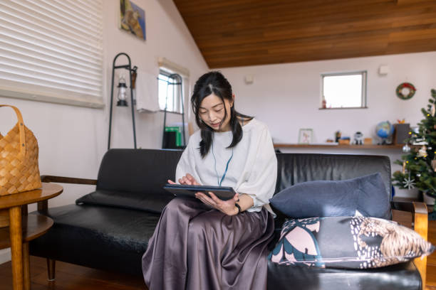 istock Japanese woman working at home, sitting on couch 1355203404