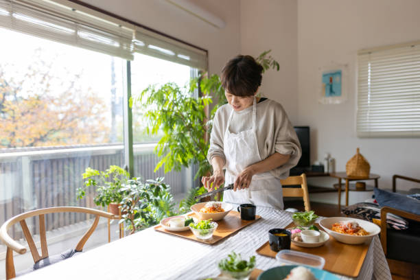 Japanese woman sprinkling cheese on spaghetti
