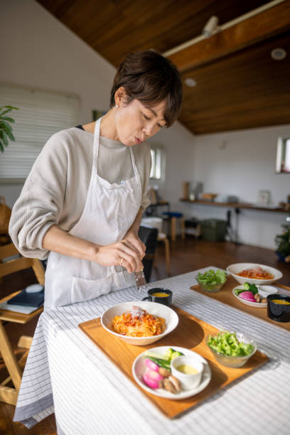 Japanese woman sprinkling cheese on spaghetti