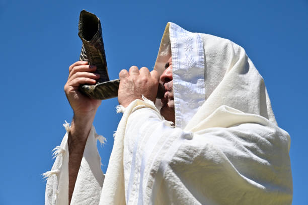 正統派ユダヤ人男性は澄んだ青空に対してショファーを吹く - hasidism ストックフォトと画像