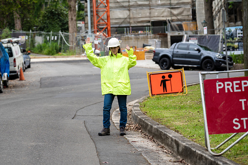 A construction site worker wearing a waterproof uniform manages road traffic at the construction site