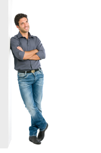 Happy smiling young man leaning against white wall with dreaming and pensive expression, copy space on the right.