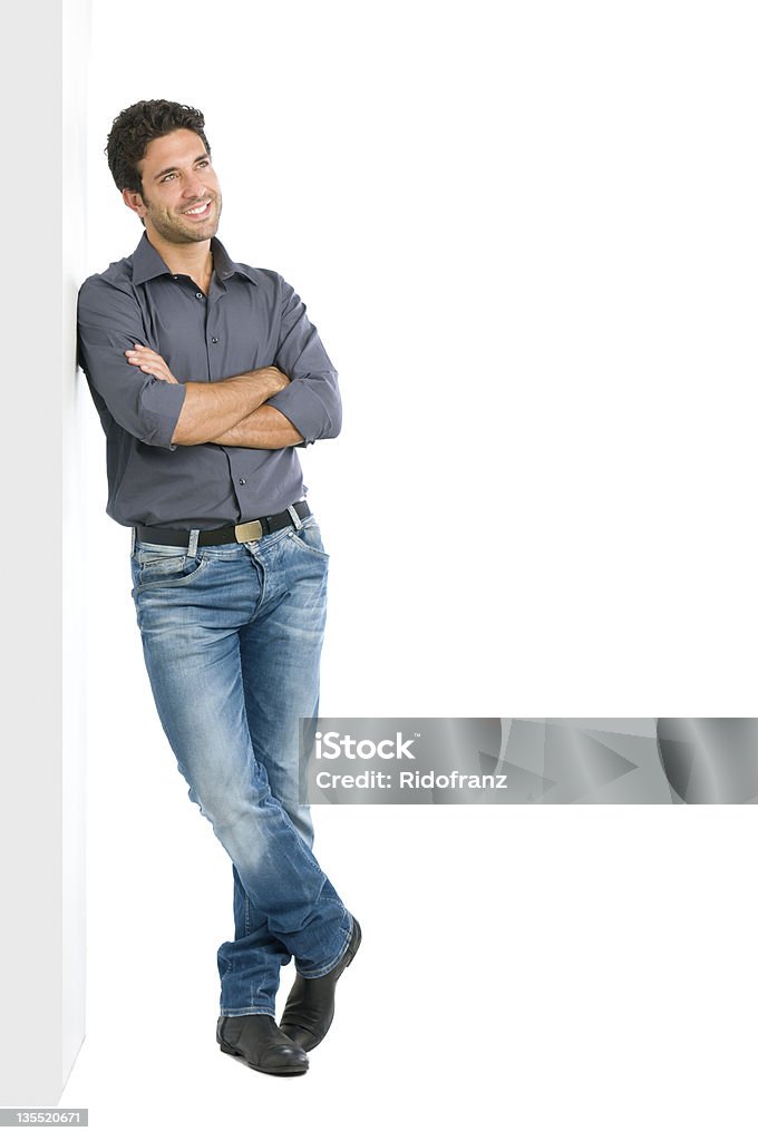 Thinking young man full length Happy smiling young man leaning against white wall with dreaming and pensive expression, copy space on the right. Men Stock Photo