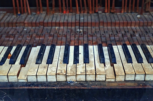 The keyboard of an old vintage piano in ruined condition.
