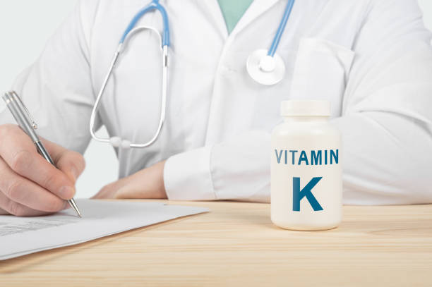 vitamina k y minerales esenciales para los seres humanos. el médico recomienda tomar vitamina k. el médico habla sobre los beneficios de la vitamina k. k vitamina - concepto de salud - capsule vitamin pill letter k medicine fotografías e imágenes de stock