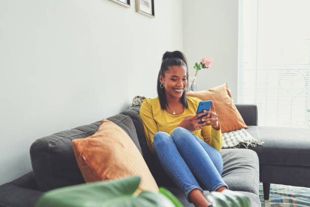 istock Shot of a young woman using a cellphone while relaxing on a sofa at home 1355221048