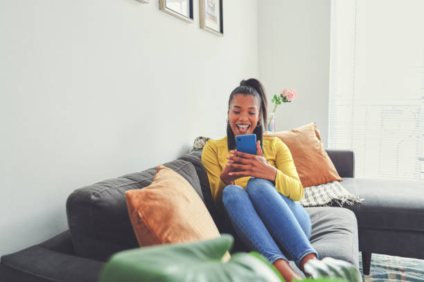 istock Shot of a young woman using a cellphone while relaxing on a sofa at home 1355221051
