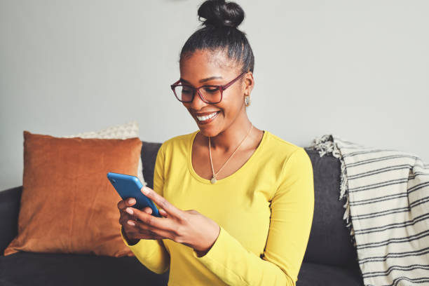 istock Shot of a young woman using a cellphone while relaxing on a sofa at home 1355221054