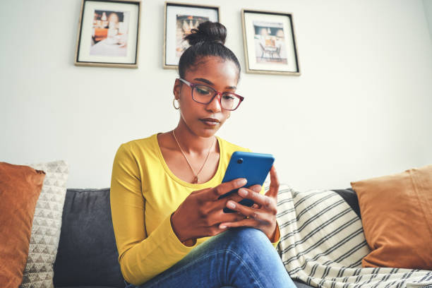 istock Shot of a young woman using a cellphone while relaxing on a sofa at home 1355221059