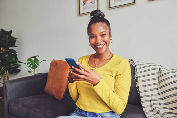 istock Portrait of a young woman using a cellphone while relaxing on a sofa at home 1355221127