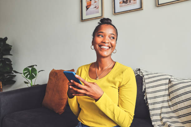 istock Shot of a young woman using a cellphone while relaxing on a sofa at home 1355221128