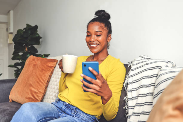 istock Shot of a young woman using a cellphone while drinking coffee at home 1355221133