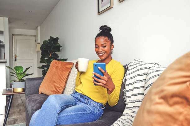 istock Shot of a young woman using a cellphone while drinking coffee at home 1355221134