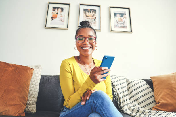 istock Portrait of a young woman using a cellphone while relaxing on a sofa at home 1355221138