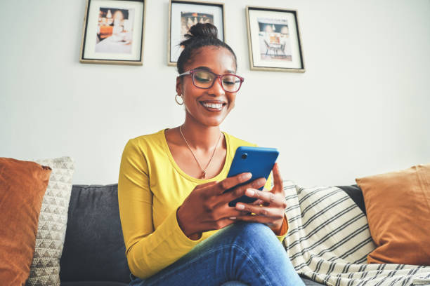 istock Shot of a young woman using a cellphone while relaxing on a sofa at home 1355221139