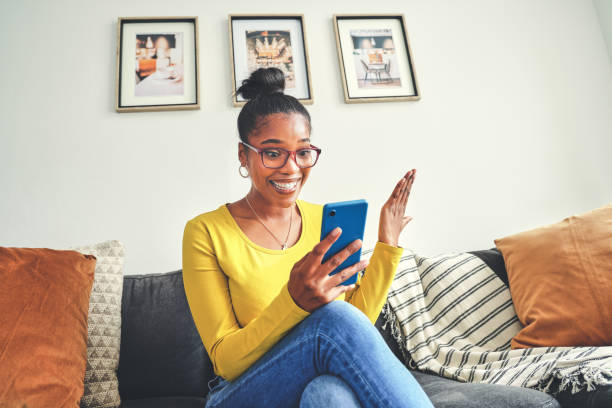 Shot of a young woman looking surprised while using a cellphone at home