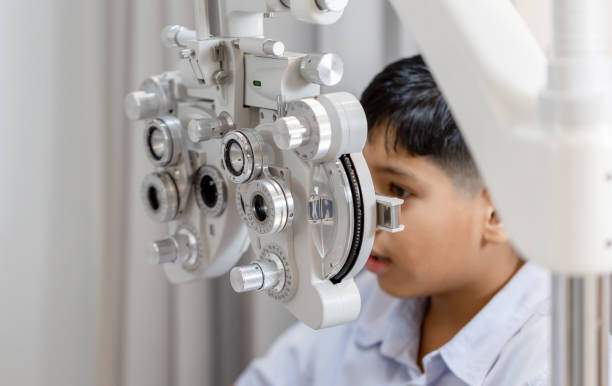 istock Boy doing eye test checking examination with optometrist in optical shop, Optometrist doing sight testing for child patient in clinic 1355221153