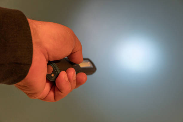 istock Pocket led flashlight in hand. illuminates blue background. Copy space 1355227768