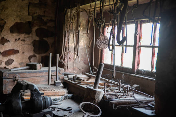 Beautiful tools in an old blacksmith shop with 12-pane window and stone construction. Cobwebs on the red window frames.