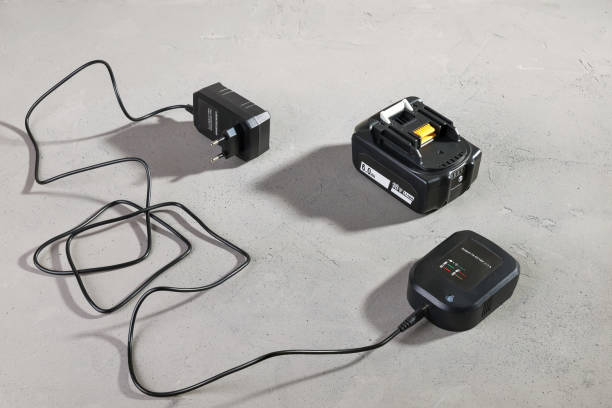 istock Powerful battery for electrical tool with disconnected charger on gray surface 1355232740