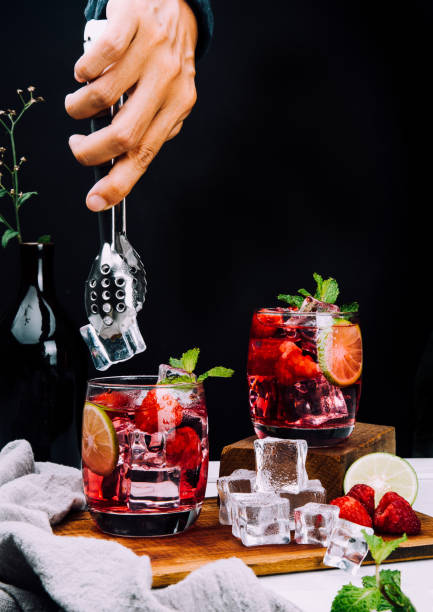 istock Refreshing summer drink with strawberry slices, lime, and mint leaf  in glasses , hand put ice on dark background beverage soda 1355233083