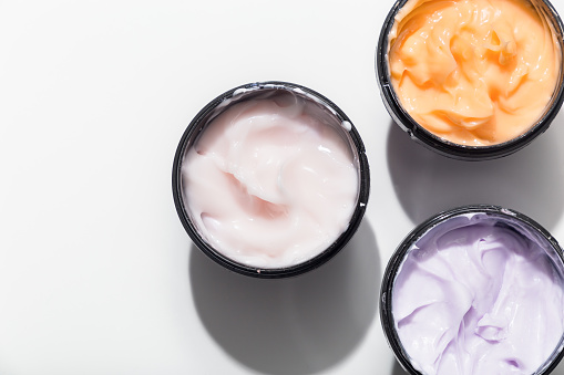 Moisturizing cream for face and body in plastic black jars on a light background. View from above