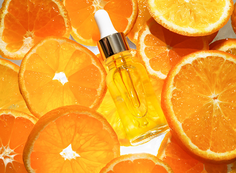 Vitamin C. Fresh citrus fruits with serum bottles, ampoules and pills. Cosmetic products. Flat lay.