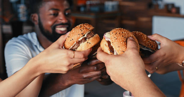 shot of a group of young friends enjoying delicious hamburgers at a diner - cafe buns eating bildbanksfoton och bilder