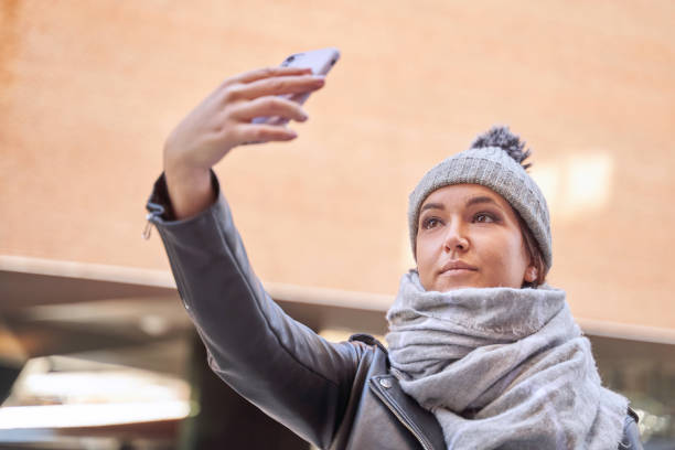istock Young female in outerwear taking selfie on sunny day 1355244610