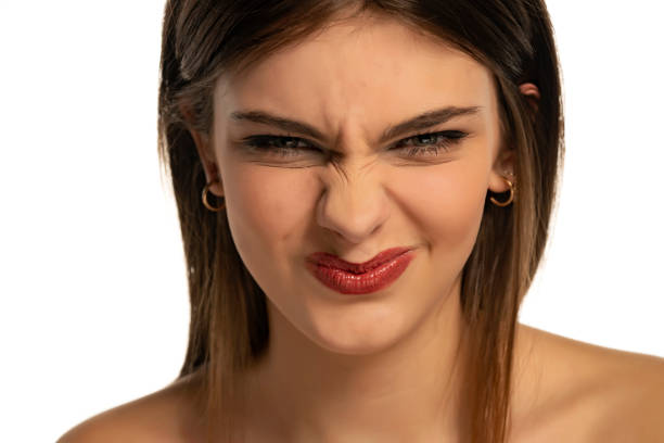 A young frowning woman with blue eyes with makeup on a white background