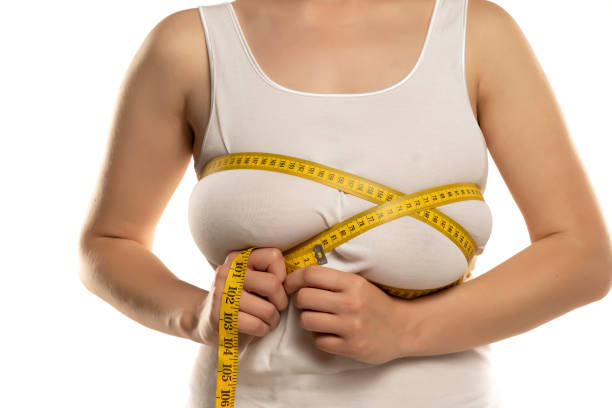 a woman measures with a measuring tape her large breasts stock photo