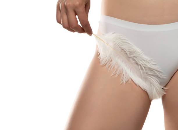 woman caresses with a feather over her smooth crotch stock photo