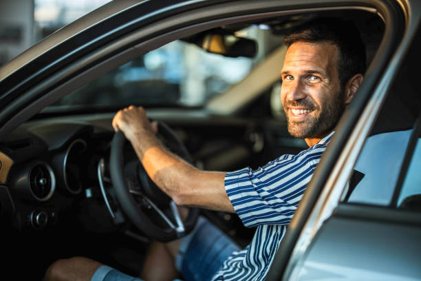 istock Young happy man testing a car in a showroom. 1355246590