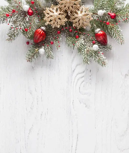 Photo of Christmas border with fir branches and  baubles on white shabby wooden board with copy space for text. Flat lay.  Christmas and New Year holidays background.