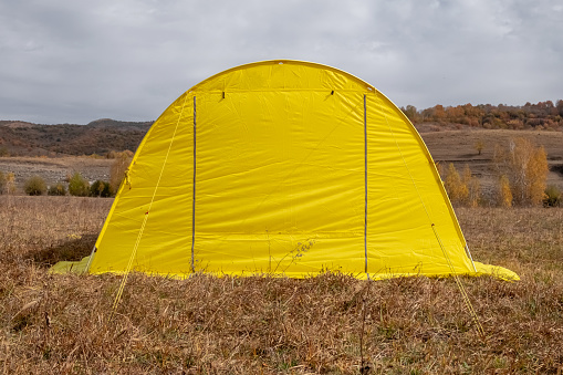 Yellow large basecamp tent on colorful mountains background. Tourism, travel, hiking in autumn season concept. Autumn in Dzhungarian Alatau, Kazakhstan. Hiking basecamp equipment.