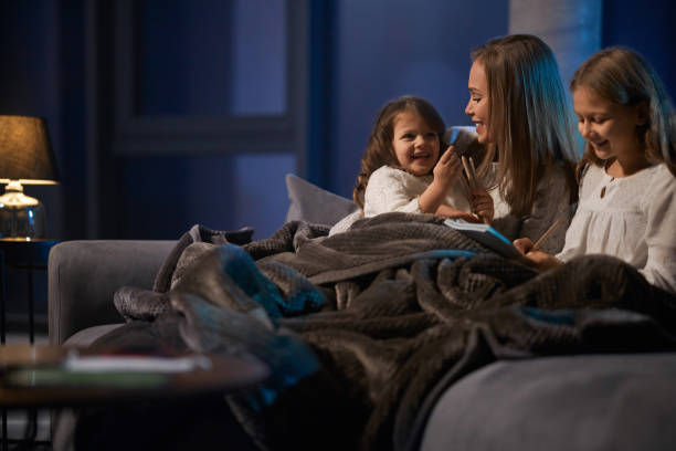 Mother reading book for daughters before going to bed stock photo