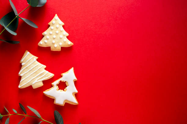 istock Christmas tree shaped cookies with eucalyptus leaves on red background with copy space 1355250514