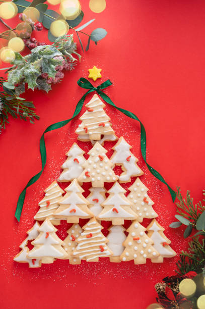 istock Christmas tree made from christmas tree shaped cookies on red background, with winter decorations and bokeh lights top view 1355250693